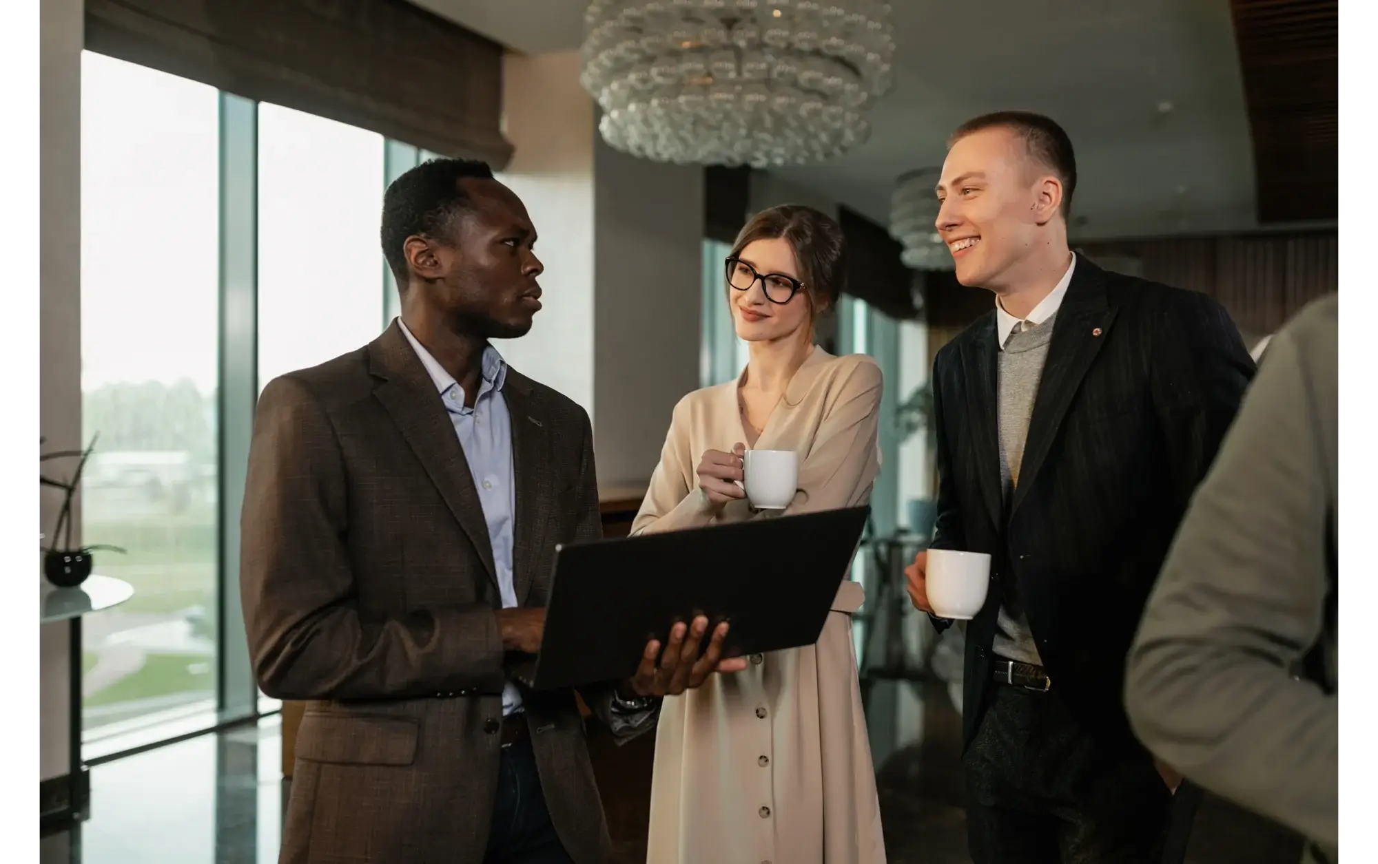 Three colleagues talking beside a laptop in an office